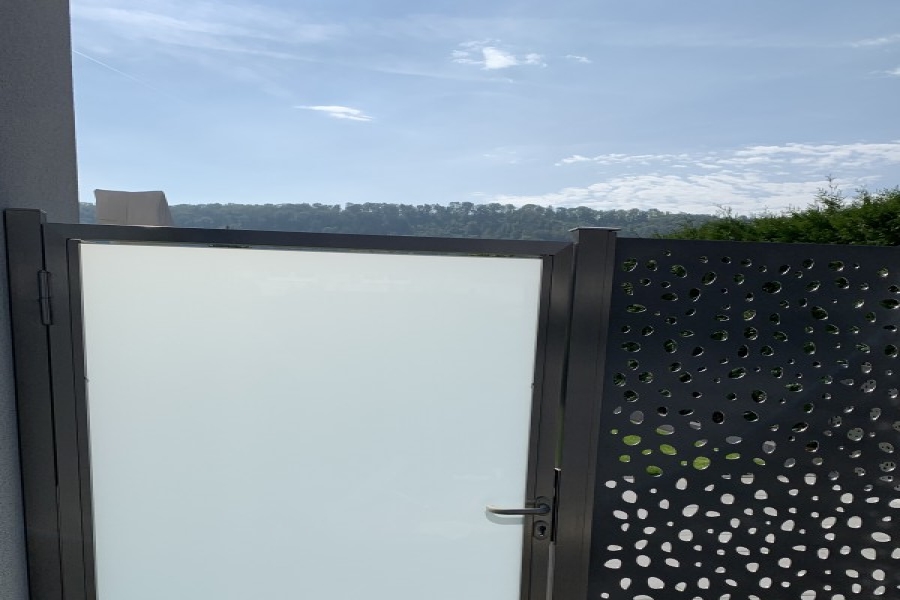 Sichtschutz Windschutz Kombination mit Aluminiumblech ausgelasert und VSG-Milchglas Gartentüre. Referenz Herznach AG