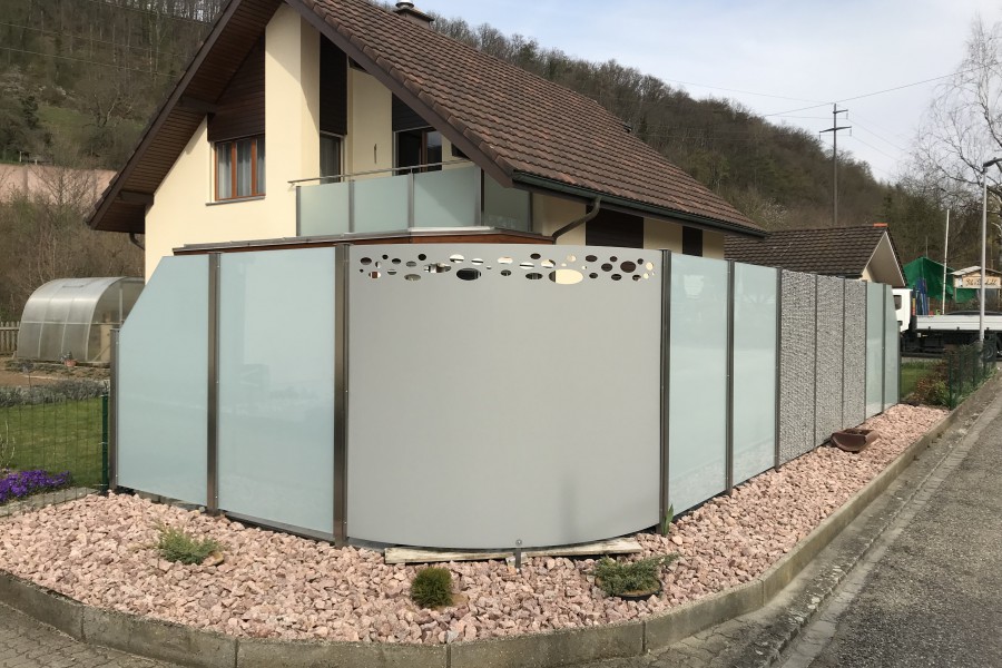 Sichtschutz Windschutz mit Steinkorb, VSG Milchglas und Aluminiumblech Elemente. Aluminiumblech Ausgelasert mit Sujet & auf Mass gerundet. Referenz Hornussen AG