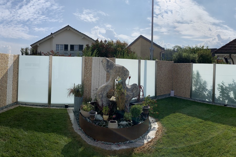 Sichtschutz Windschutz Kombination mit Steinkrben und VSG-Milchglas Elementen. Gartentre mit Aluminiumblecheinsatz mit Familienname ausgelasert. Referenz Sisseln AG